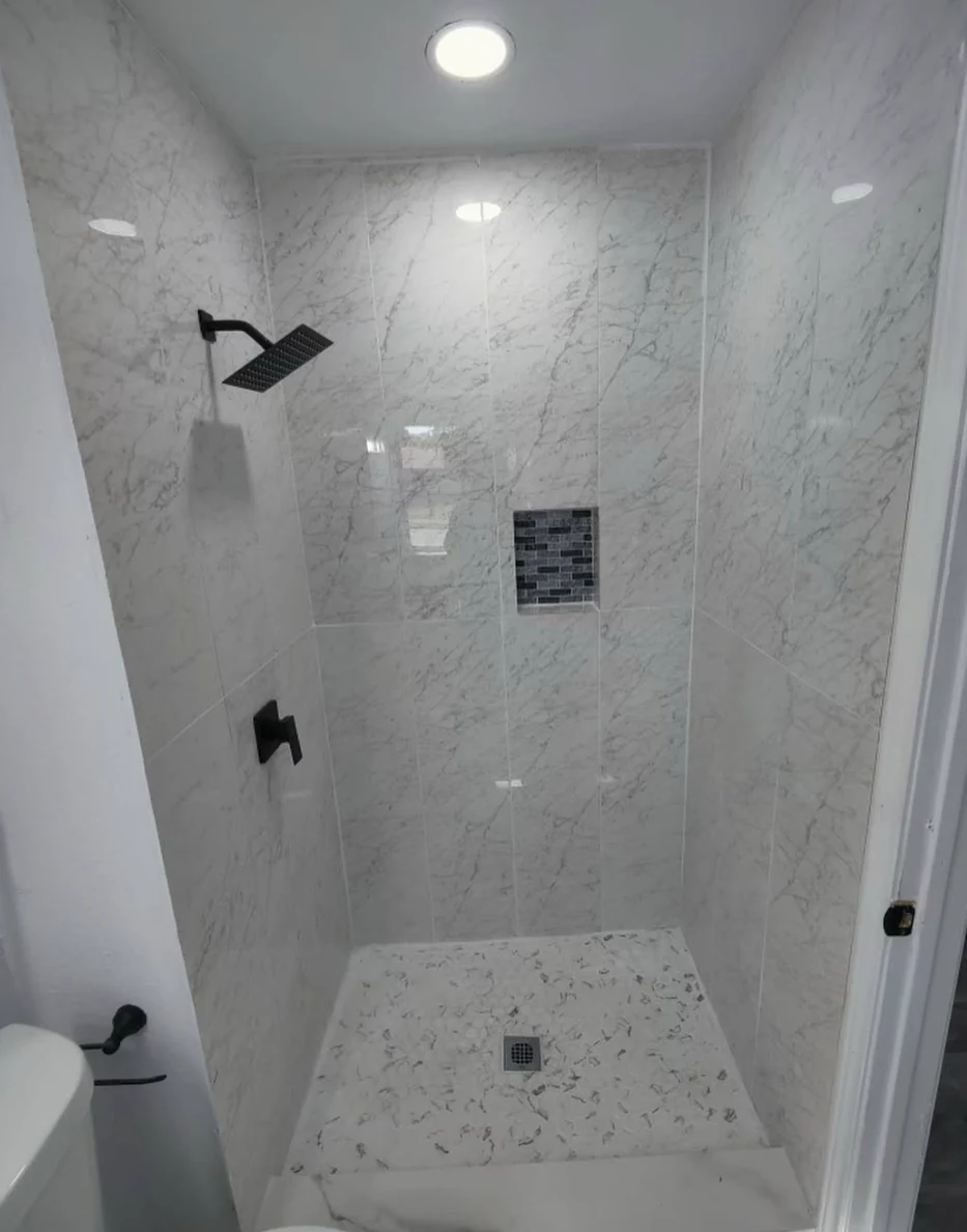 Walk-in shower tile with marble-look porcelain and modern black fixtures